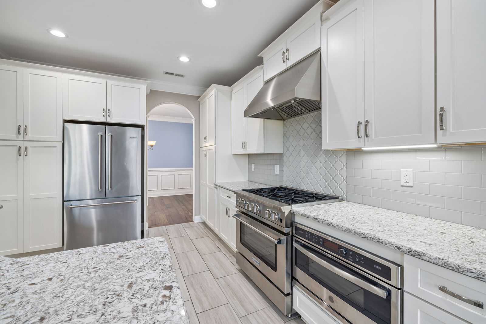 Real kitchen interior with white cabinetry, island seating, and pendant lighting